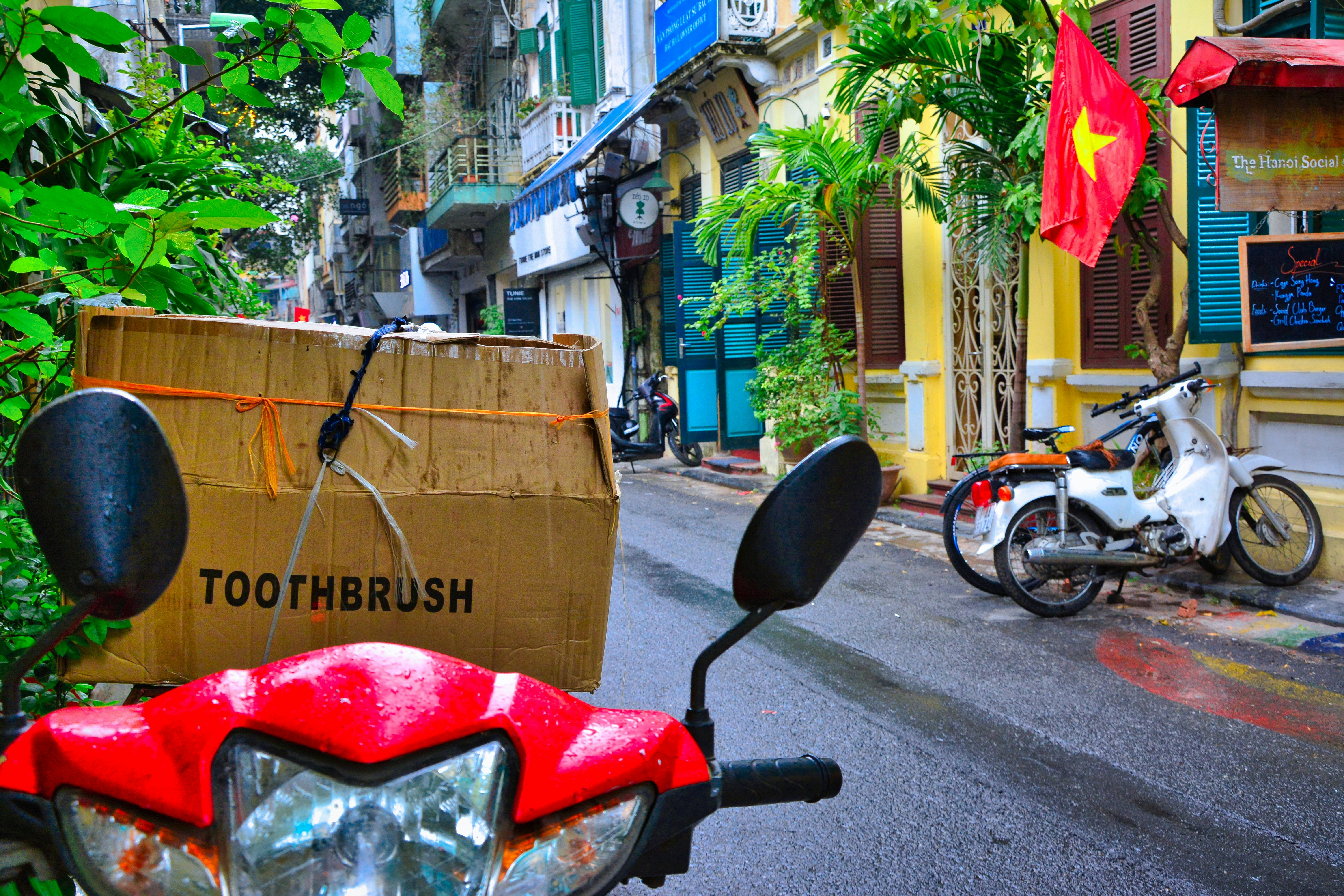 a red scooter parked on the side of a street, 