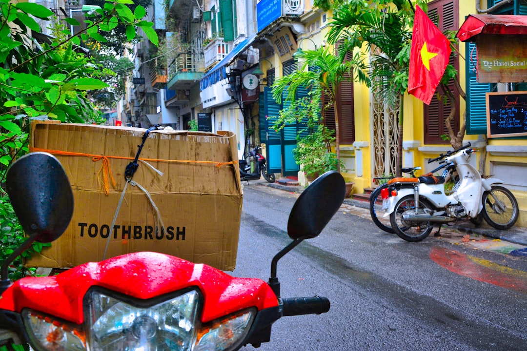 a red scooter parked on the side of a street,