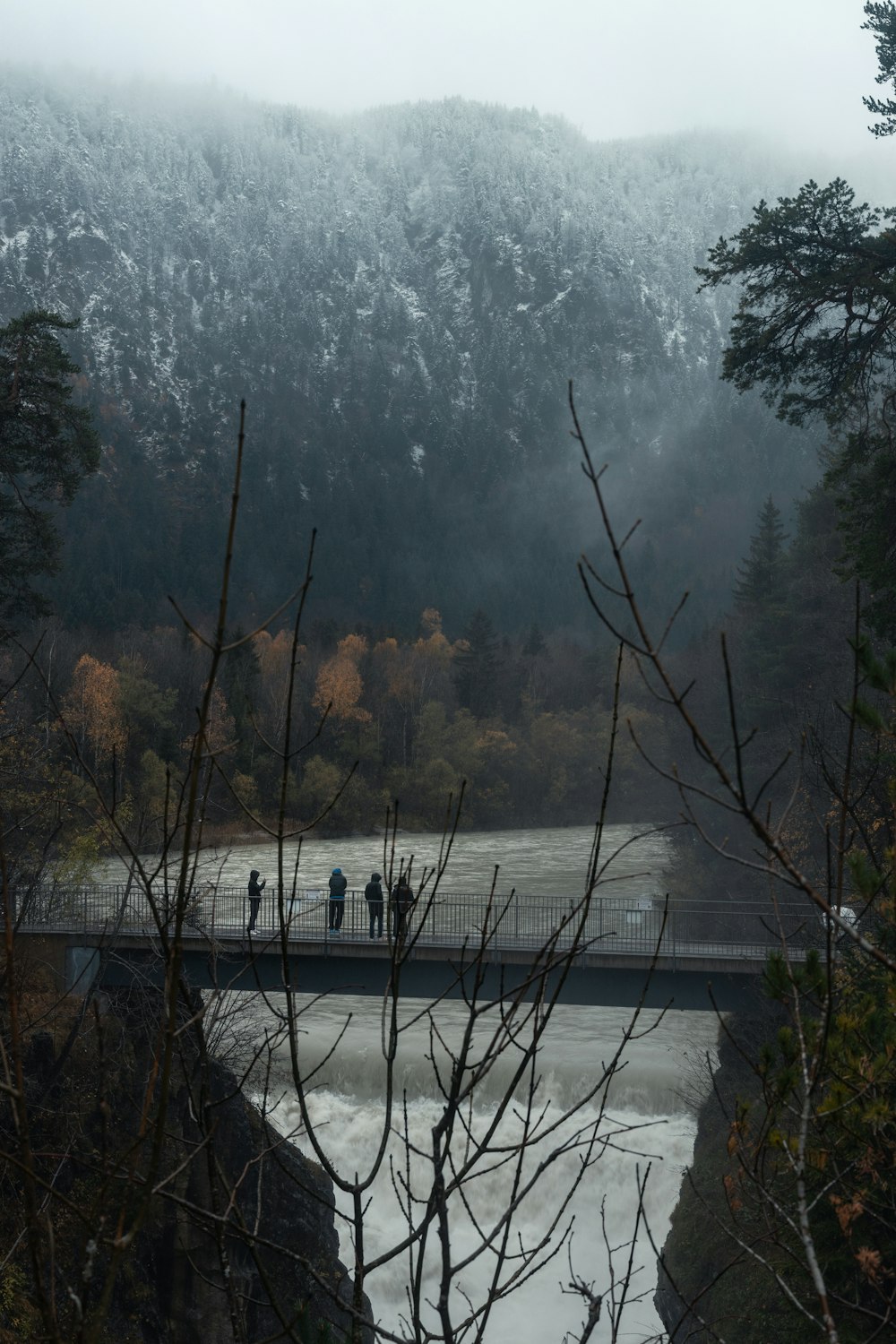 um grupo de pessoas em pé em uma ponte sobre um rio
