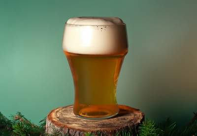 a glass of beer sitting on top of a tree stump