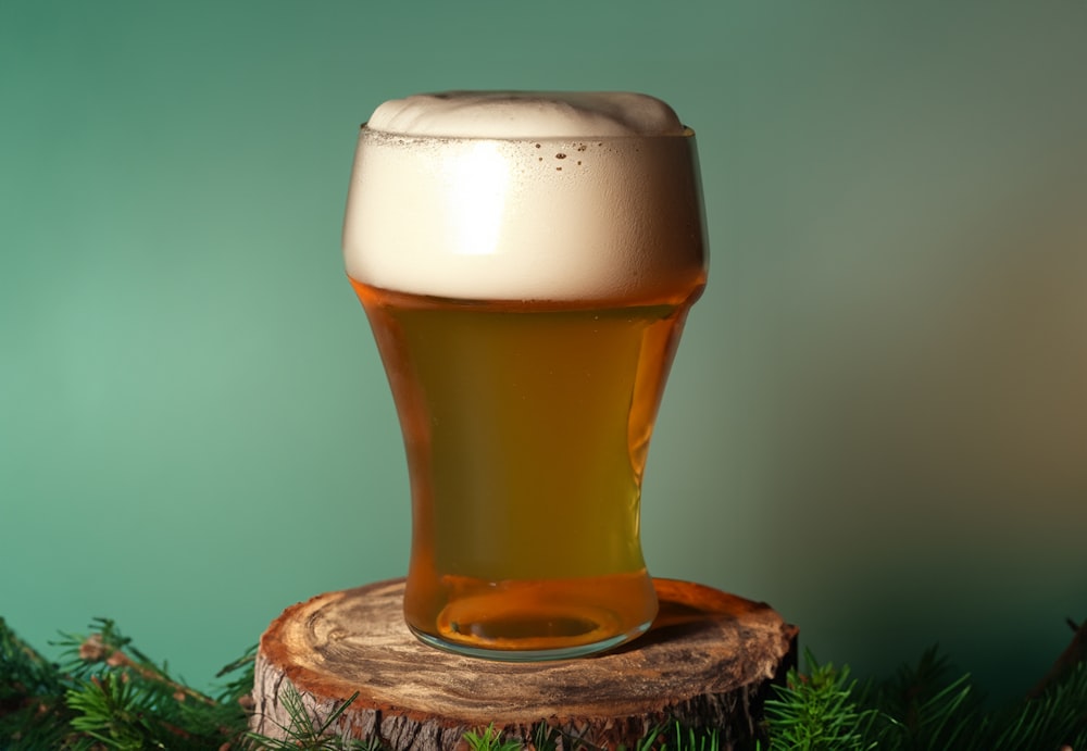 a glass of beer sitting on top of a tree stump