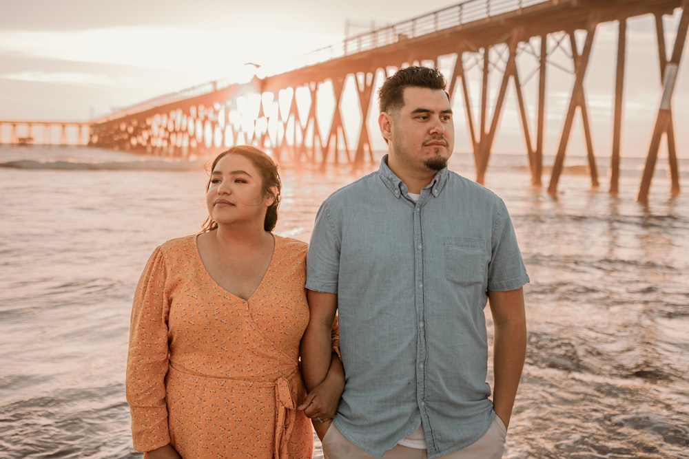 a man and a woman standing next to each other near the ocean