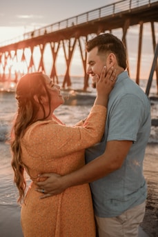 A candid moment of a couple embracing during a sunset at a beach, capturing genuine emotions.