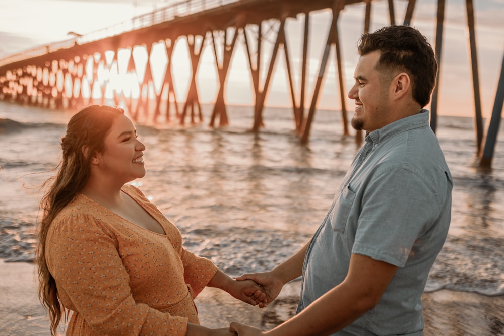 a man and a woman holding hands on the beach