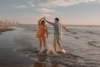 Close-up of happy dancers laughing and holding tickets with the ocean in the background.