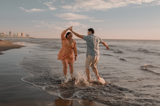 Close-up of happy dancers laughing and holding tickets with the ocean in the background.