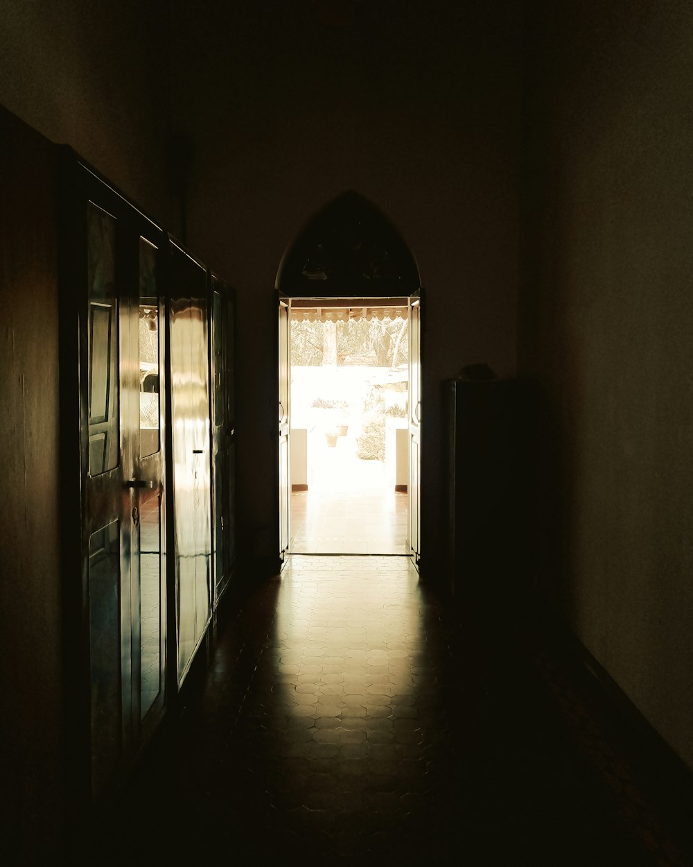a dark hallway with an open door leading to another room