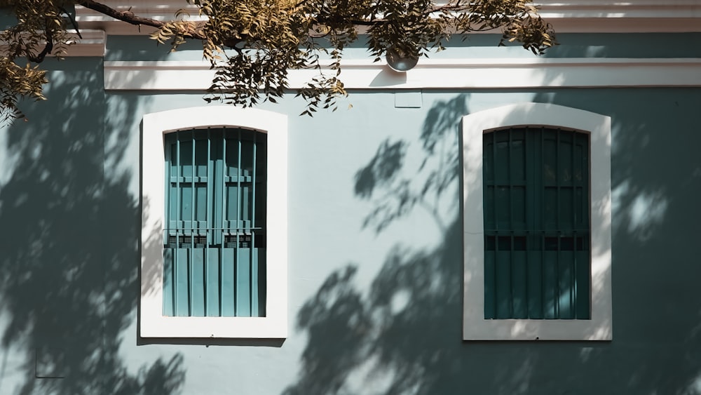 a blue building with two windows and bars on the windows