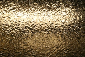 Textured surface of golden onyx illuminated to highlight its natural translucency and layers.