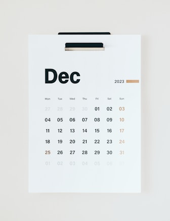 A minimalistic wall calendar for December 2023, with days of the week listed at the top starting from Monday. The calendar is predominantly white with black text and a subtle touch of gold used for Sundays and the number 25, suggesting Christmas.