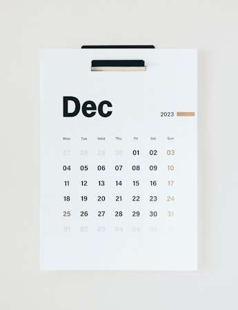 A minimalistic wall calendar for December 2023, with days of the week listed at the top starting from Monday. The calendar is predominantly white with black text and a subtle touch of gold used for Sundays and the number 25, suggesting Christmas.