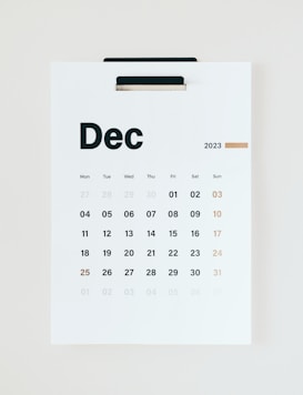 A minimalistic wall calendar for December 2023, with days of the week listed at the top starting from Monday. The calendar is predominantly white with black text and a subtle touch of gold used for Sundays and the number 25, suggesting Christmas.
