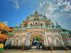 a large white and green building with a sky background