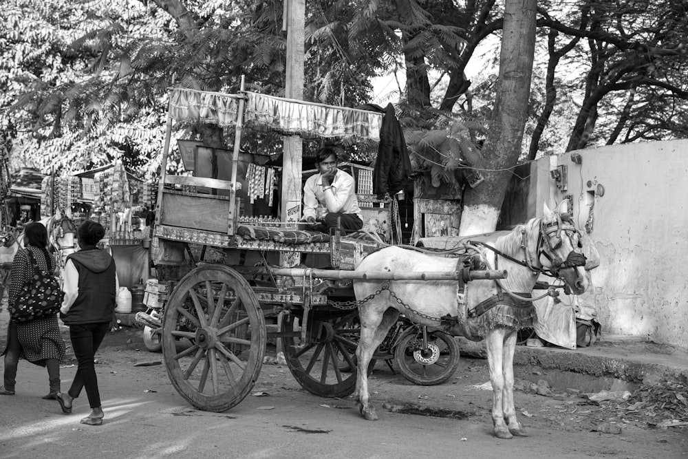 a black and white photo of a horse pulling a cart