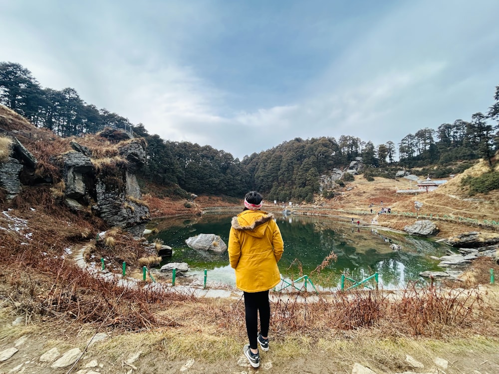 a person in a yellow jacket looking at a lake