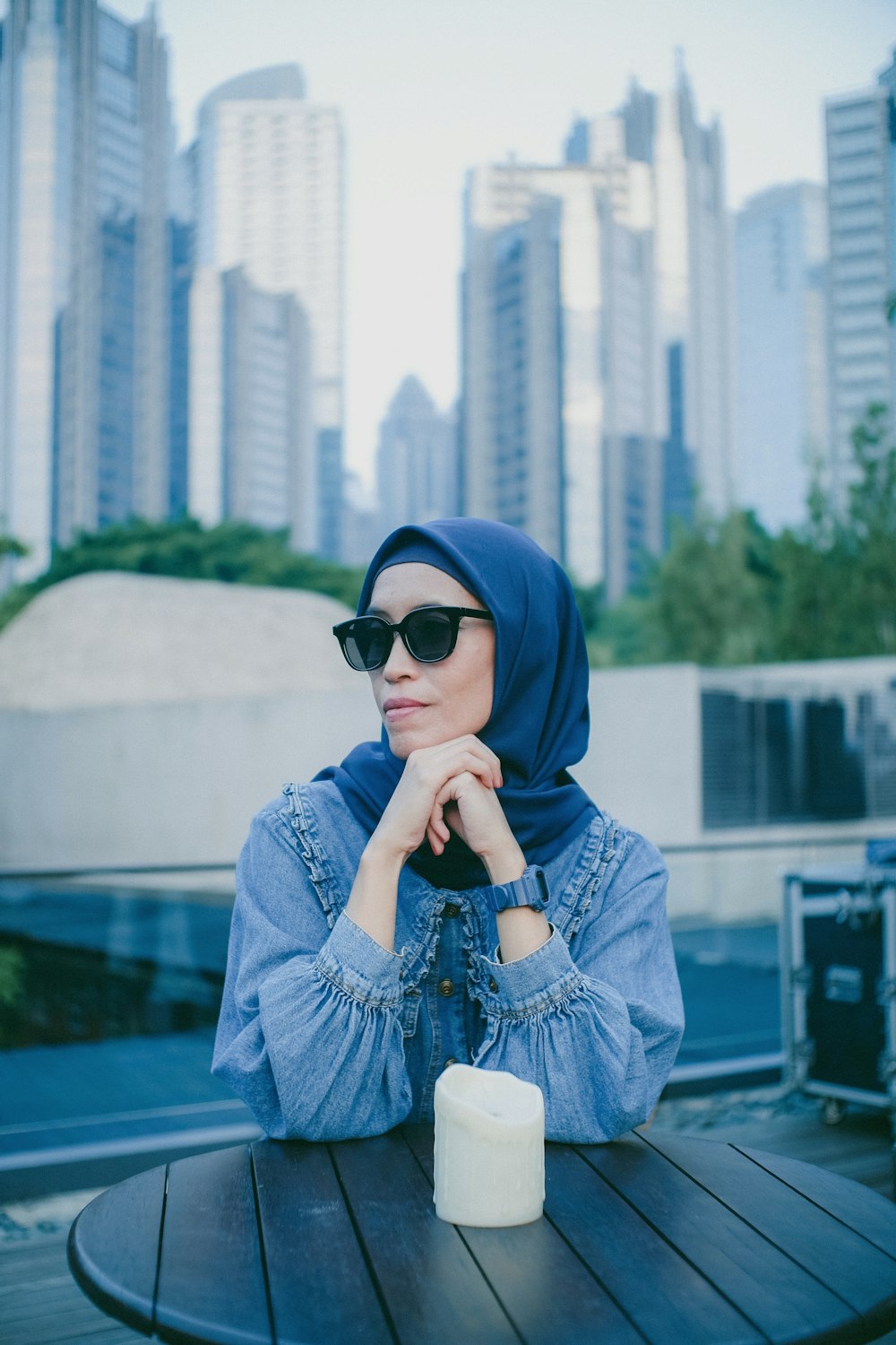a woman sitting at a table wearing a blue hijab