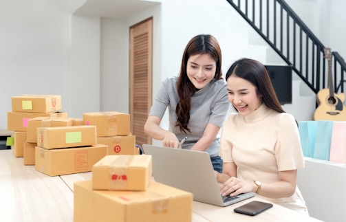 Smiling women collaborating over a laptop in a bright office.