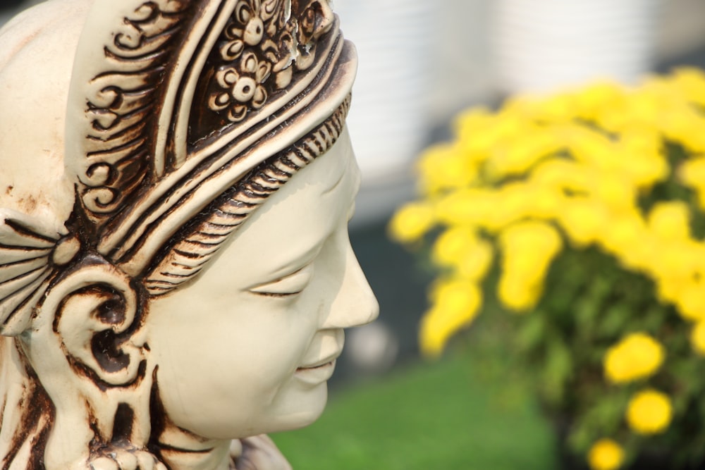 a close up of a statue of a person with flowers in the background