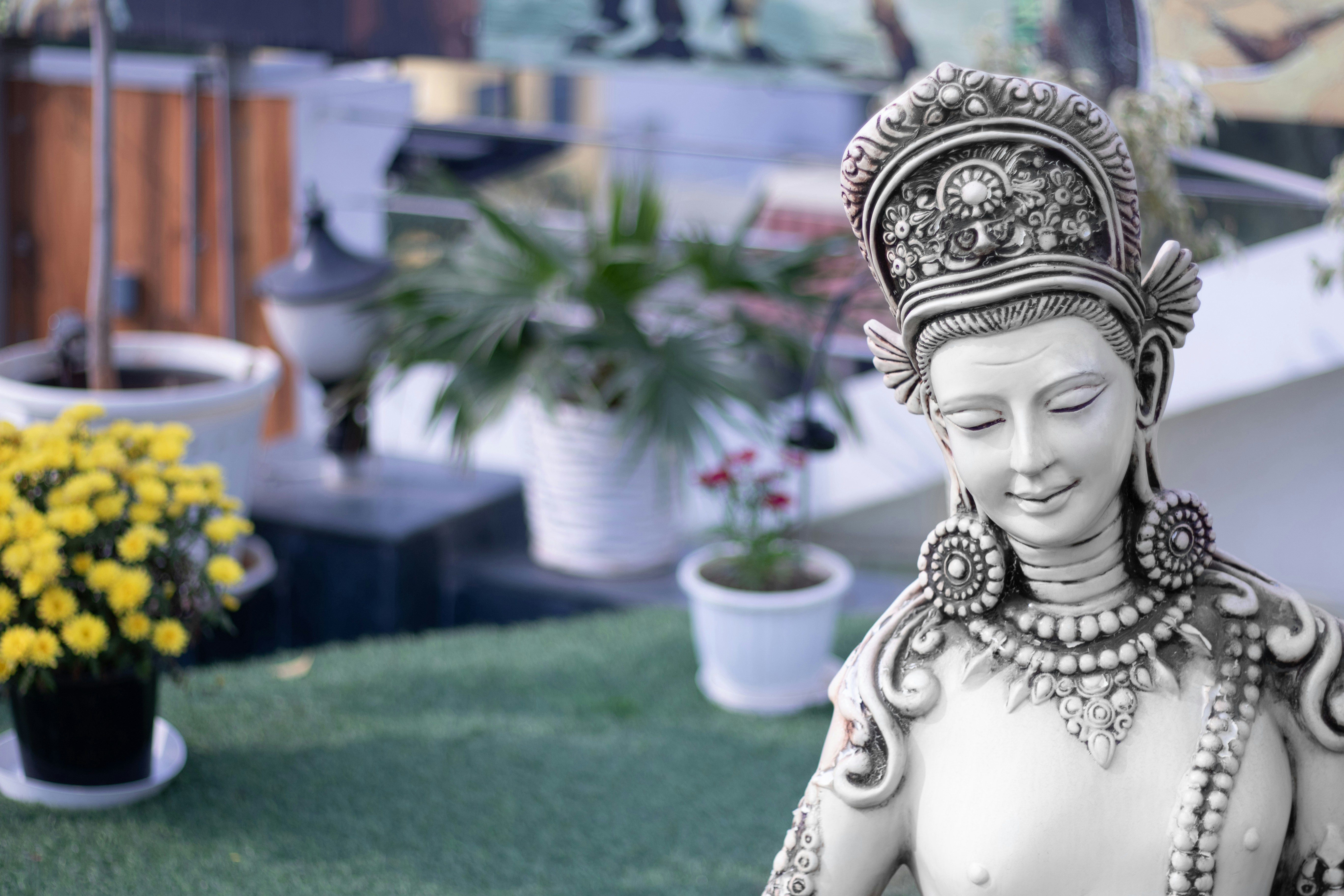 A statue of a woman sitting on top of a lush green field