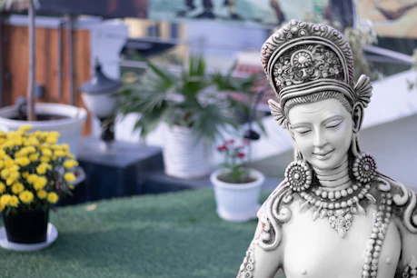 a statue of a woman sitting on top of a lush green field
