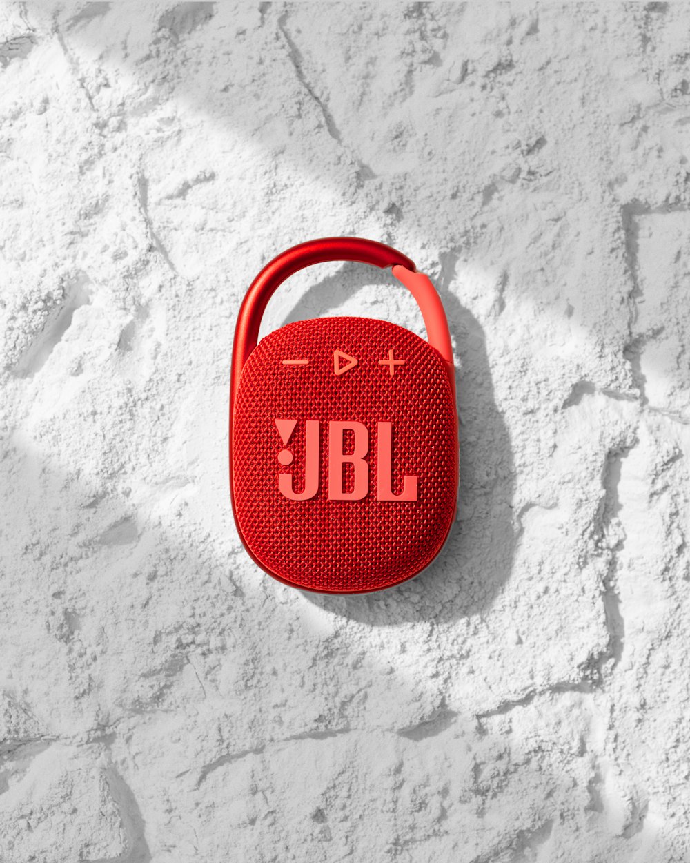 a red jbl speaker sitting on top of a white wall