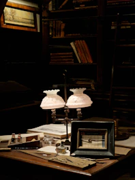 A dimly lit vintage study room with scattered poetry books and a quill pen beside a flickering candle.