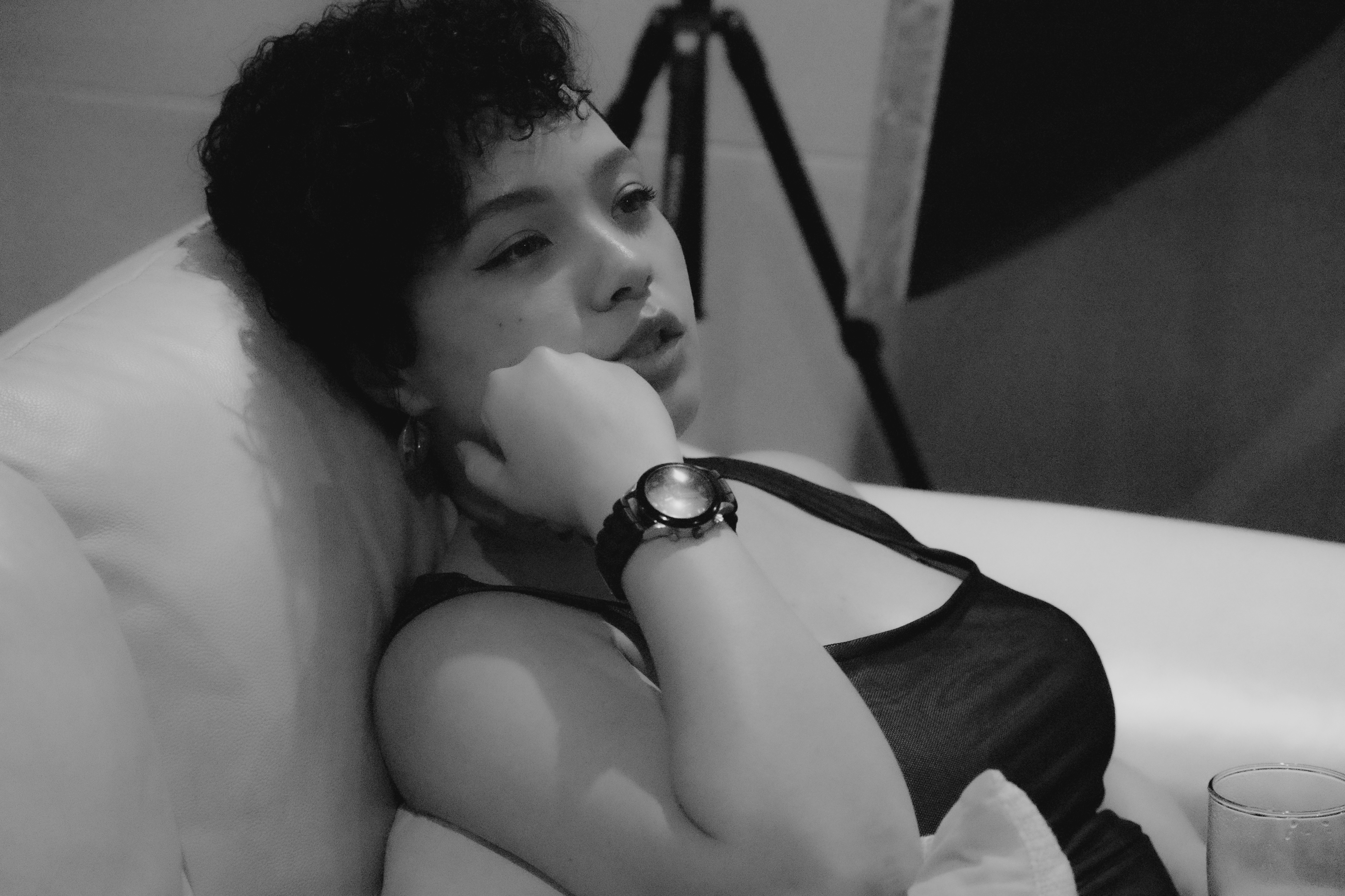 eine Frau, die mit einem Glas Wasser auf einem Bett liegt