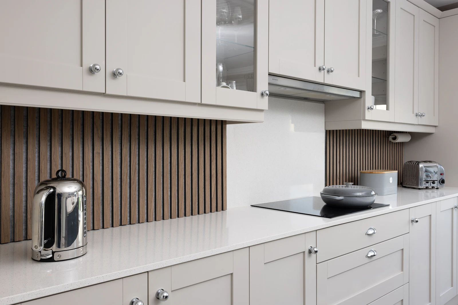 Fitted shaker-style kitchen with slatted wood splashback and quartz worktops