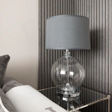 Close-up of a modern lamp casting a warm glow on a stylish side table.