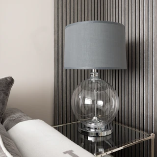 Close-up of a sleek gold-accented lamp and modern vase on a minimalist wooden side table.