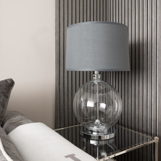 A sleek ceramic globe table lamp illuminating a bedside table.