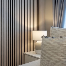 a white bed sitting next to a window covered in curtains