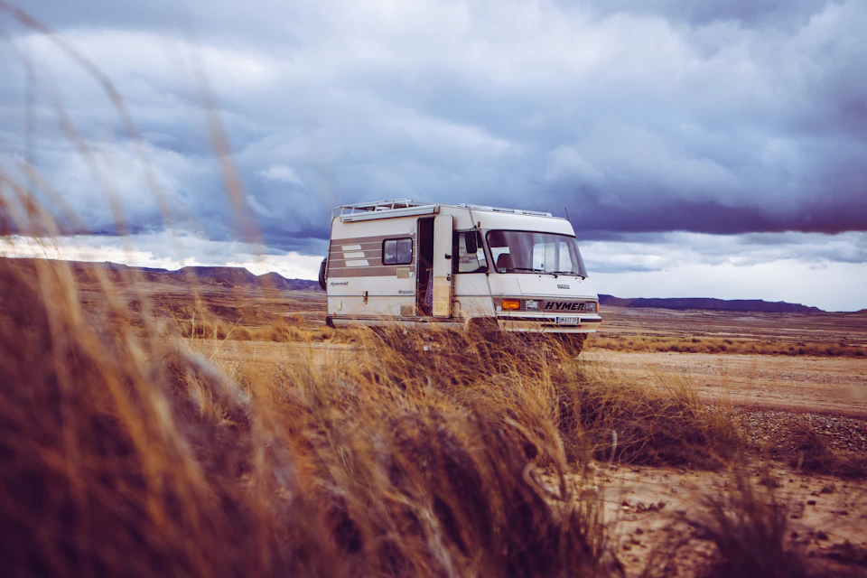 White and gray camper van parked on dirt road with open door facing right side
