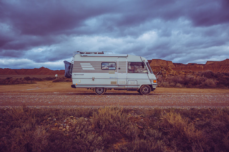 White and gray camper van parked on a dirt road in a desert landscape