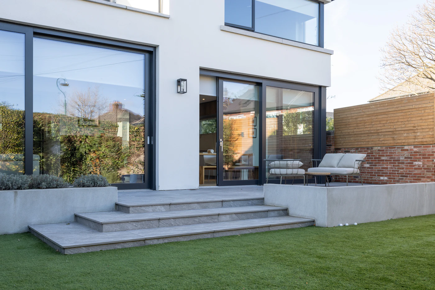 Modern home rear patio with steps and lawn at the lower level