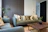 A modern living room corner featuring elegant storage units in deep forest green and gold accents.