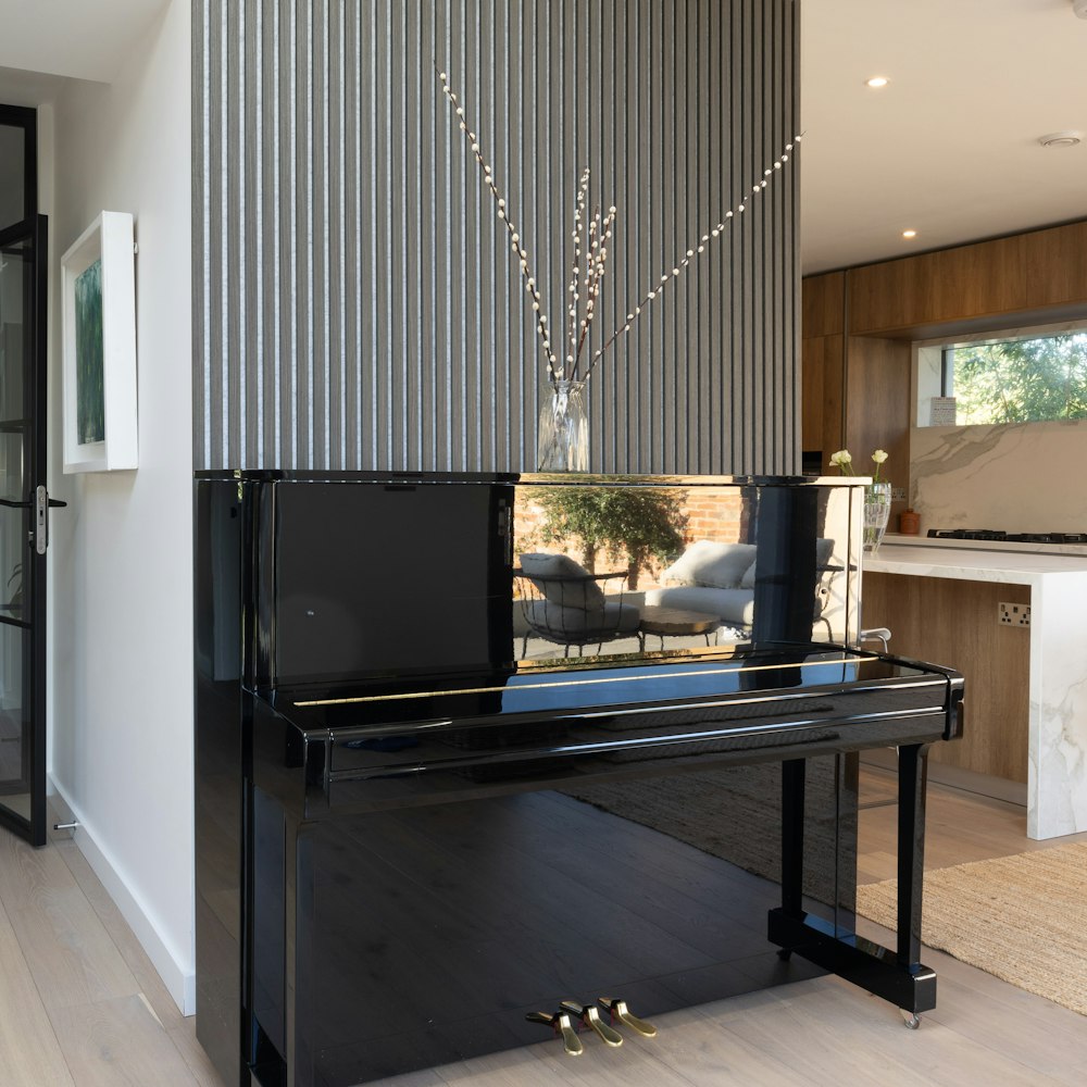 um piano preto sentado em uma sala de estar ao lado de uma janela