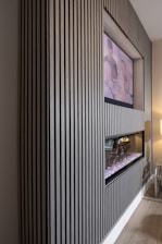 A close-up of a sleek media wall featuring charcoal built-ins and subtle Venetian plaster accents.