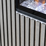 Vertical wooden slats are arranged next to a glass panel containing decorative ice-like crystals. The wood appears to have a natural finish, and the glass panel reflects some light, creating a contrast between the materials.