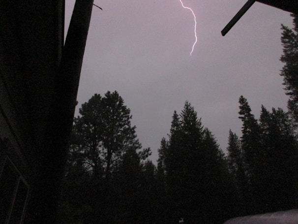 A haunted house silhouette against a stormy night sky with lightning.