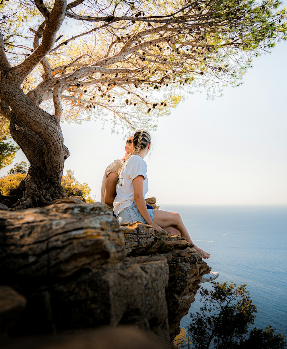 a man and woman sitting on top of a cliff