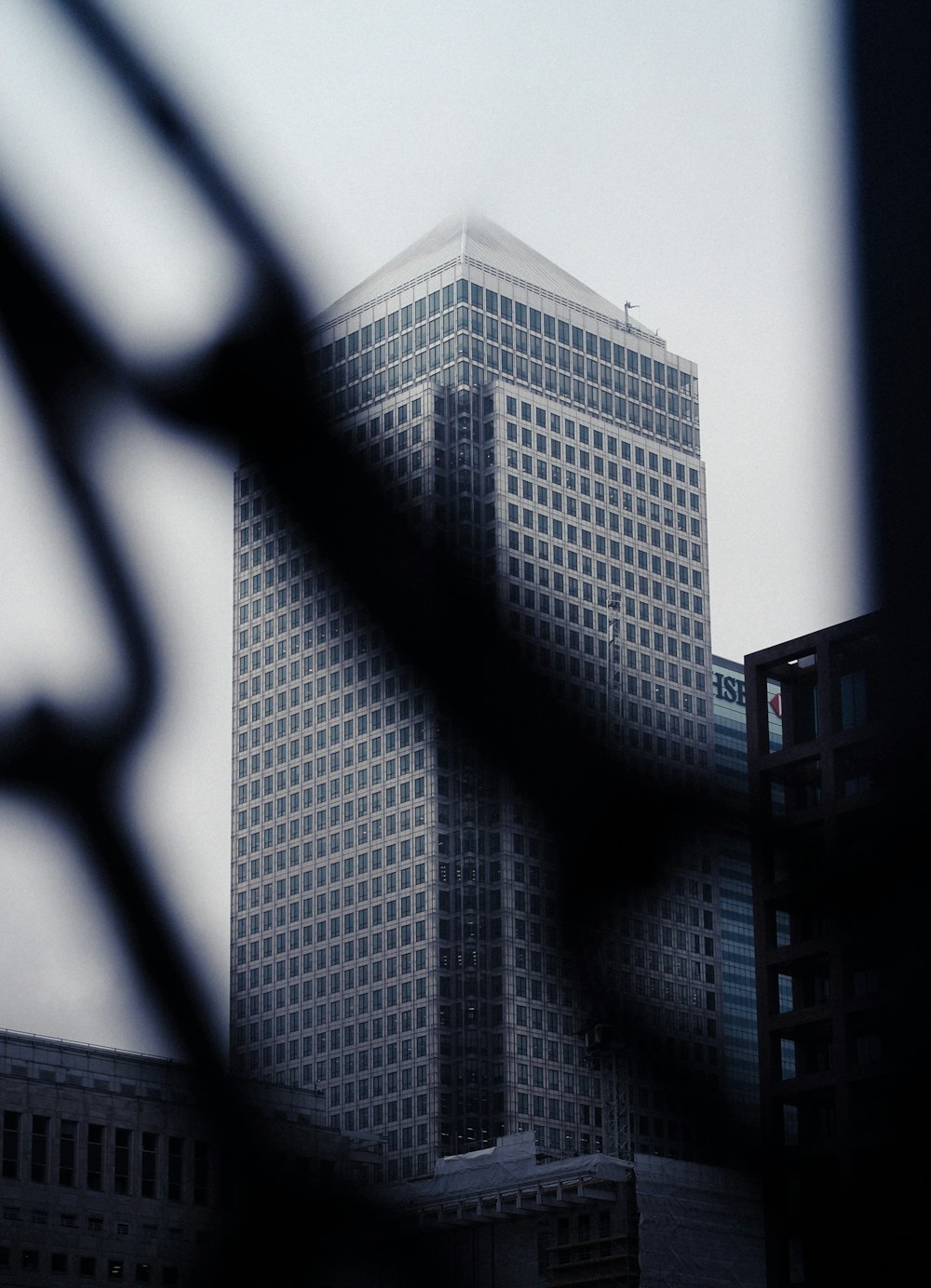 a tall building is seen through a chain link fence