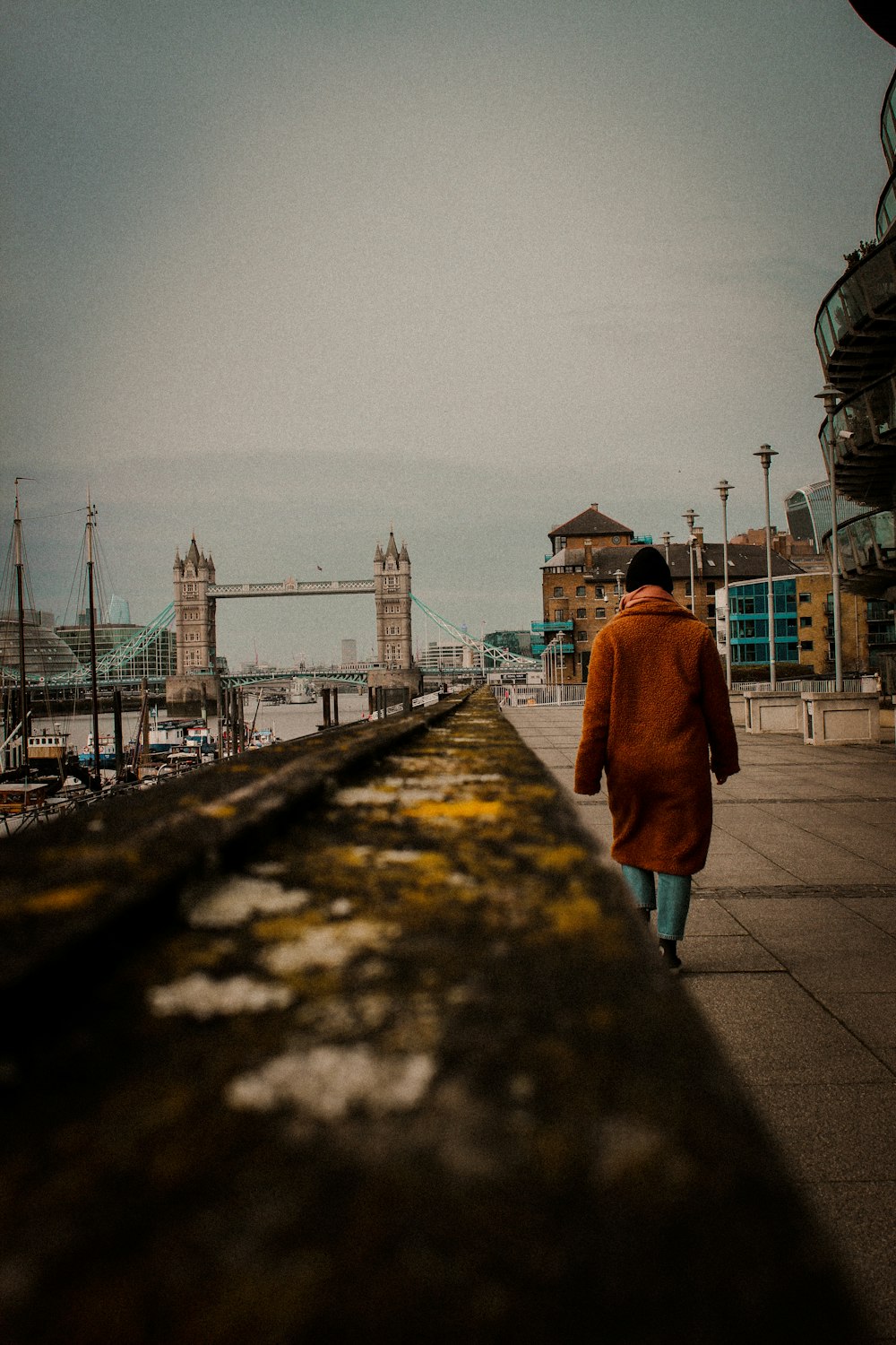 a man walking down a sidewalk next to a bridge