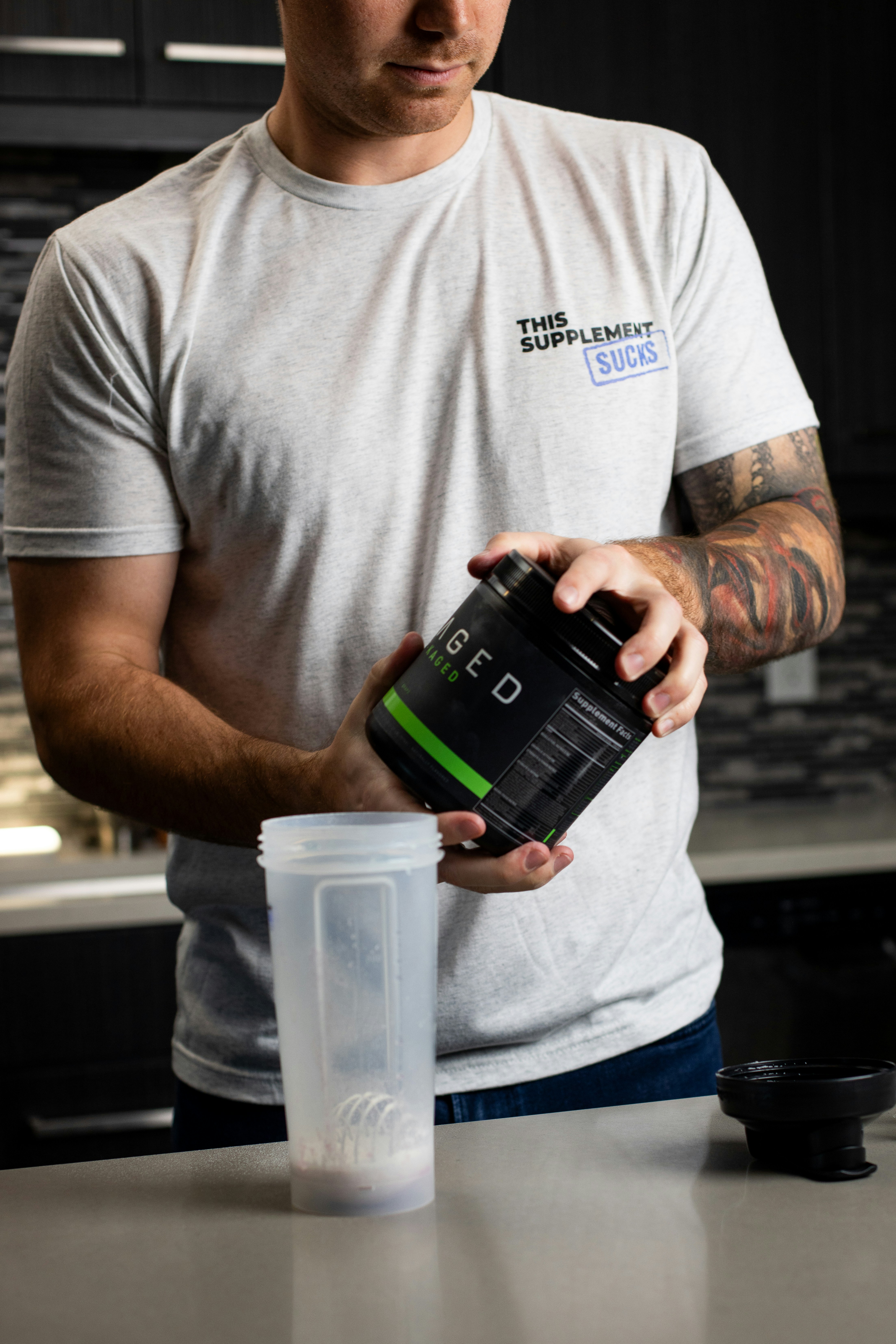 Um homem de camiseta branca está segurando uma bebida