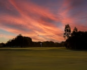 A scenic view of a golf course at sunset.