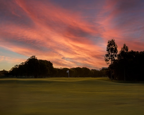A scenic view of a golf course at sunset.