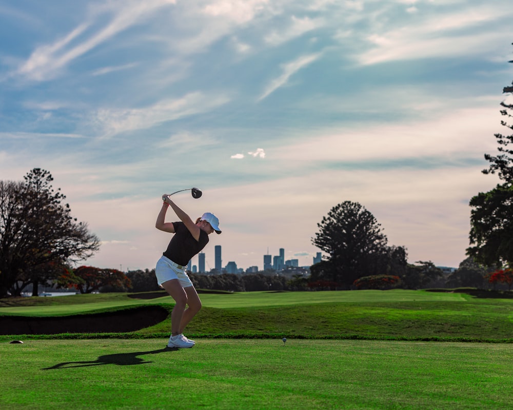 a man swinging a golf club on top of a green field