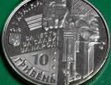 A Ukrainian coin from 2018 with a design that includes a hand gripping a sword and a block of text in Cyrillic. The coin has intricate detailing, including the Ukrainian coat of arms and a denomination of 10 hryvnias. The background features a green surface.