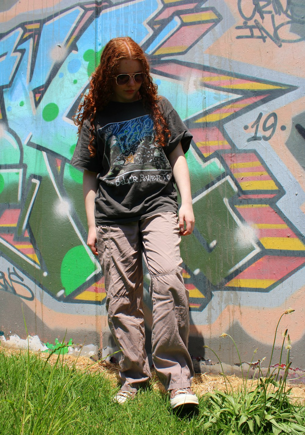 a woman standing in front of a graffiti wall