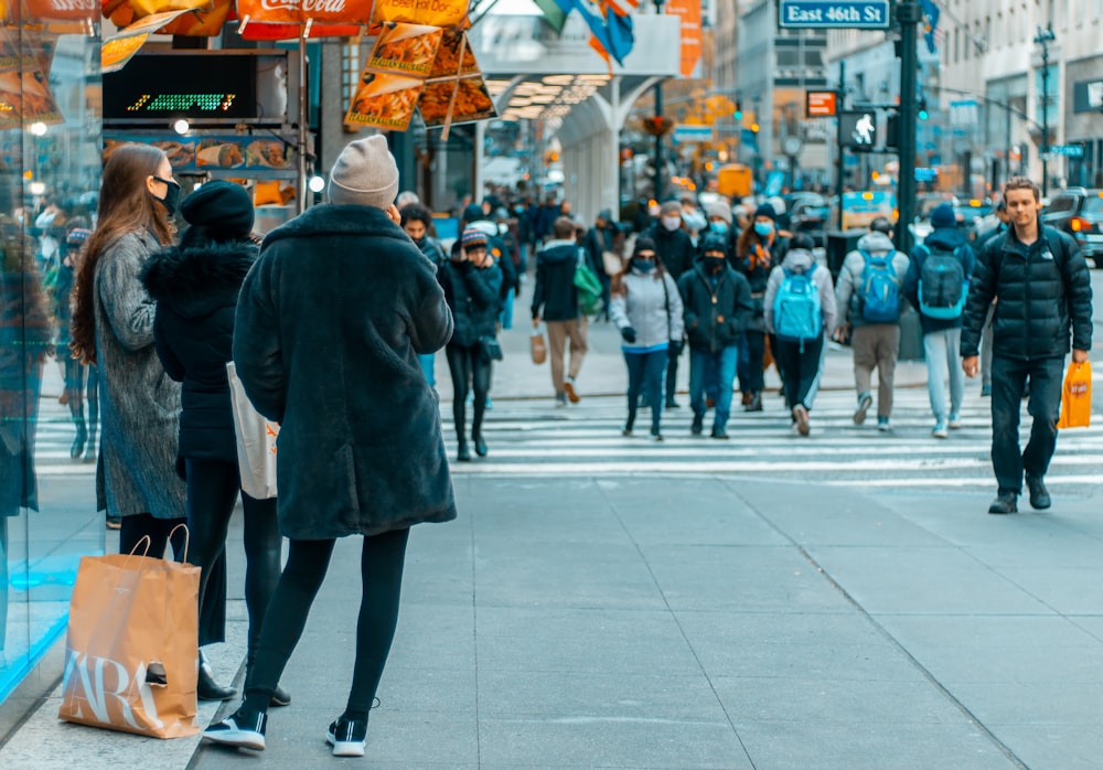 a crowd of people walking down a street next to tall buildings